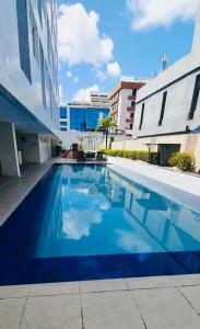 a large blue swimming pool next to a building at Imperial Suítes in João Pessoa