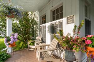 - une terrasse couverte avec 2 chaises et des fleurs dans l'établissement Inn at Silver Maple Farm, à East Chatham