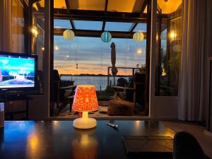 una lámpara sentada en una mesa frente a un televisor en The Outpost Lakehouse- enjoy our house at Reeuwijkse Plassen - near Gouda en Reeuwijk