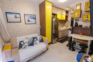 a living room with a couch and a kitchen at Flat Solar Água 127 - Family & Friends in Pipa