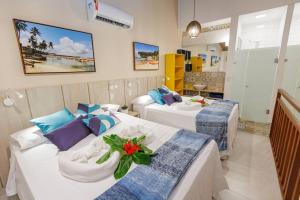um quarto de hotel com duas camas com flores em Flat Solar Água 127 - Family & Friends em Pipa