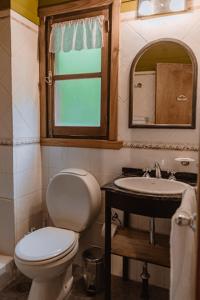 a bathroom with a toilet and a sink and a mirror at Cabañas Quetrihue in Villa La Angostura