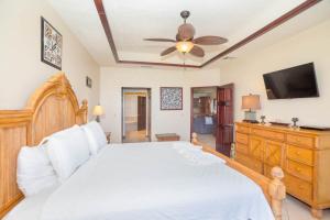 a bedroom with a white bed and a flat screen tv at Del Playa Penthouse #5 Condo in West End