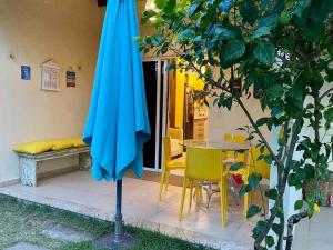 ein blauer Regenschirm neben einem Tisch und Stühlen in der Unterkunft Flat Solar Água 127 - Family & Friends in Pipa