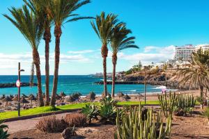 a view of a beach with palm trees and the ocean at Tenerifeopenhome Luxury comfort Studio in playa Las Americas in Playa de las Americas