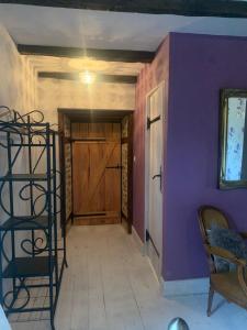 einen Flur mit lila Wänden und einer Holztür in der Unterkunft Bay Tree Corner in Saint-Bazile