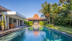 a villa with a swimming pool in front of a house at Villa Markisa Echo Beach in Canggu