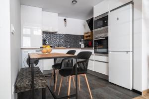 a kitchen with white cabinets and a wooden table and chairs at BEL APPARTEMENT A ETRENER PROCHE DE LA PLAGE in Valencia