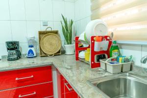 a kitchen counter with a sink and red cabinets at Integral Consults Apartment in Abuja