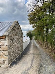 a dirt road with a stone wall and a building at Toms Cottage in Longford