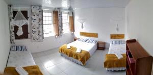 a bedroom with two beds and a desk and windows at O Pouso Sobrado in Mucugê