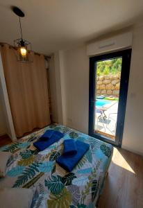 a bedroom with a bed with blue pillows and a window at La Belle Vie en Alaric in Douzens