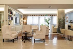 Soave Roxy Apartments في سواف: غرفة انتظار وكراسي بيضاء وطاولة