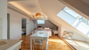 Il dispose d'une cuisine et d'un salon avec une table et des chaises blanches. dans l'établissement Le Grenier Cosy, T2 classé meublé de tourisme, à Rodez