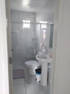 a white bathroom with a toilet and a sink at O Pouso Sobrado in Mucugê