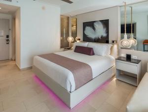 a bedroom with a large white bed with purple lighting at Royalton CHIC Punta Cana, An Autograph Collection All-Inclusive Resort & Casino, Adults Only in Punta Cana