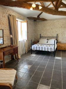 een slaapkamer met een bed, een bureau en een raam bij Naturo-gites in Nieul-le-Virouil