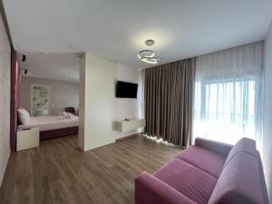 uma sala de estar com um sofá roxo e uma cama em Hotel LEON - Beach Front em Shëngjin