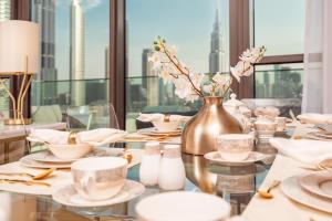 einen Tisch mit Platten und eine Vase mit Blumen in der Unterkunft Elite Royal Apartment - Panoramic Full Burj Khalifa, Fountain & Skyline View - ACed direct connection to Dubai Mall - Governor in Dubai