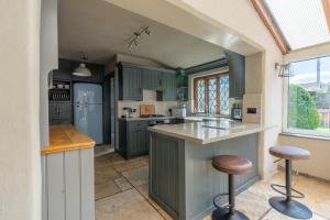 a kitchen with green cabinets and bar stools at Remarkable 4-Bed Cottage in Cearleon in Newport