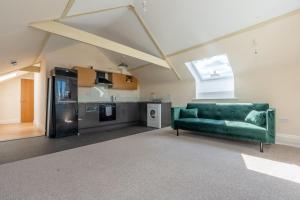 a living room with a green couch and a kitchen at 1 Bed Flat - Sleeps 2 - Parking - Wifi in Newport