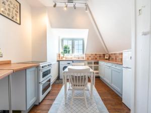 a kitchen with blue cabinets and a white chair at Pass the Keys Victorian Flat A Stones Throw From Hampton Court in East Molesey