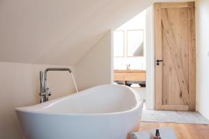 a white bath tub in a room with a wooden door at Slufterhoeve in De Cocksdorp