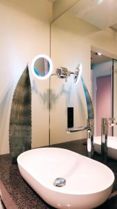 lavabo blanco en el baño con espejo en Zum Löwen Design Hotel Resort & Spa en Duderstadt