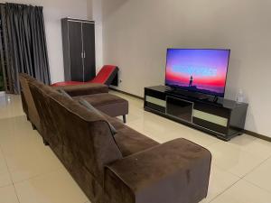 Homestay Balik Pulau في باليك بولاو: غرفة معيشة مع أريكة وتلفزيون بشاشة مسطحة