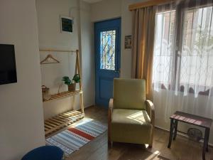 a living room with a chair and a blue door at Dalgaci Deniz Konukevi in Ayvalık