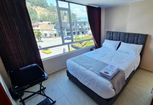 ein Schlafzimmer mit einem Bett und einem großen Fenster in der Unterkunft Hotel San Jose in Duitama