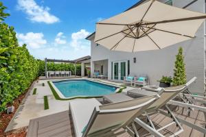 un patio con sombrilla y piscina en Glamour Villa - 5BR, Heated Pool, Game Haven L23, en Miami