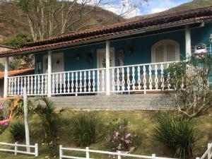 a blue house with a white fence in front of it at Pousada Recanto dos Arcos in Conservatória