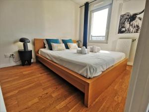 a bedroom with a large bed with white sheets and blue pillows at CÔTÉ GARE - Gare - Centre-ville - Parking - Netflix - Wifi - Disney+ - Terrasse in Annecy