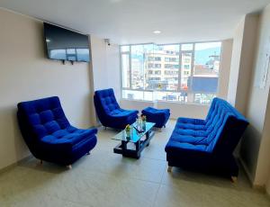a waiting room with blue chairs and a tv at Hotel San Jose in Duitama