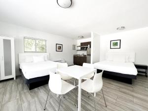 two beds in a room with a table and chairs at Beach Gardens in Fort Lauderdale