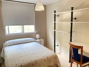 1 dormitorio con cama, silla y estanterías en Acogedor chalet familiar en la Sierra Calderona, en Nàquera