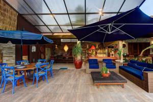 un patio con sedie blu, tavoli e ombrelloni di Casa Oásis com Sauna, Hidro e Piscina by Carpediem ad Aquiraz