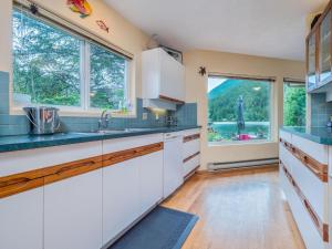 eine Küche mit weißen Schränken und einem großen Fenster in der Unterkunft North Lake Waterfront Home in Egmont