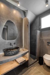 a bathroom with a stone sink and a toilet at Mirabelle Luxury Villas in Plaka