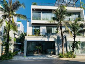 a building with palm trees in front of it at Joy Villa Đại Lải - 5 phòng ngủ in Phúc Yên