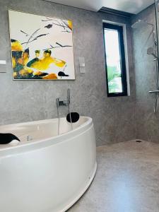 baño con bañera blanca y una pintura en la pared en Joy Villa Flamingo Đại Lải - 5 phòng ngủ, en Phúc Yên