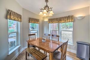 a dining room with a wooden table and chairs and windows at 8 Mi to Big Bear Lake and Village Sugarloaf Cabin! in Sugarloaf