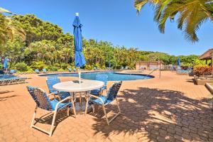 una mesa con sillas y una sombrilla frente a una piscina en Peaceful Condo with Amenities Steps to Beach! en Maunaloa