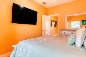 a bedroom with an orange wall with a flat screen tv at East Shore Paradise #448 in Clearwater Beach