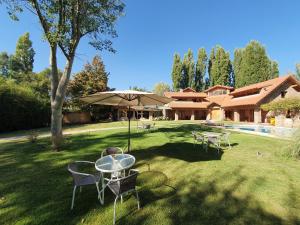 una mesa, sillas y una sombrilla en un patio en La Bignonia Posada en Chacras de Coria