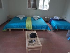 two twin beds in a room with a table at Pousada Rural Simpatia in Caculi