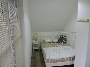 バラトンセペズドにあるSzepezd OAK villaの白い小さなベッドルーム(ベビーベッド、テーブル付)