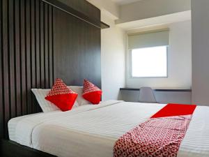 um quarto com uma cama grande e almofadas vermelhas e brancas em OYO 91593 San San Rooms Apartment Gunung Putri Square em Parungdengdek