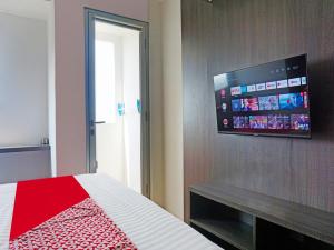 1 dormitorio con 1 cama y TV de pantalla plana en la pared en OYO 91593 San San Rooms Apartment Gunung Putri Square, en Parungdengdek